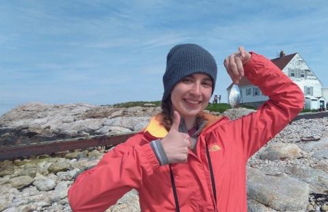 woman holding butterfish wearing binoculars thumbs up