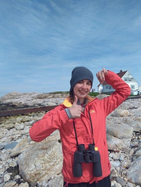 woman holding butterfish wearing binoculars thumbs up