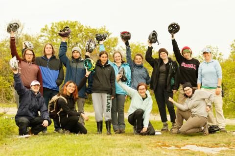 a class full of students holding up their helmets