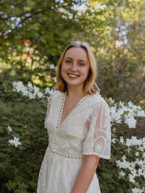 woman in white dress in front of flowering tree
